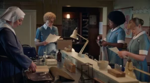 Three midwives and a children's aid worker in the TV show Call the Midwife talking during their morning meeting.